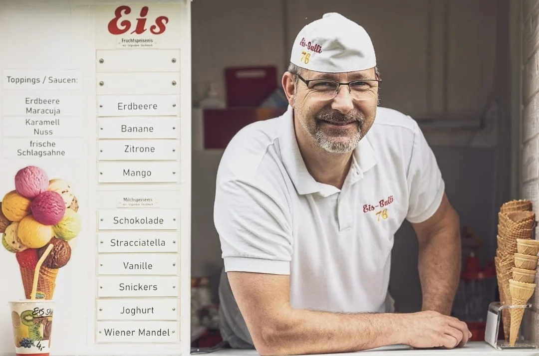 Der Eismann des Eis-Bulli 76 lächelt am Verkaufsfenster