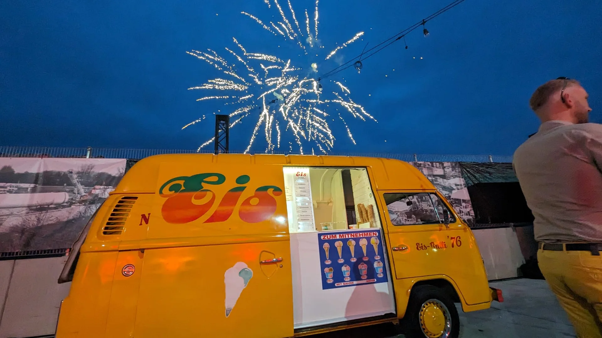 Der orange Eis-Bulli 76 bei einer Abendveranstaltung mit Feuerwerk